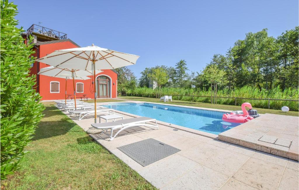 a swimming pool with an umbrella and chairs and an inflatable at Porta Di Valle 2 in Cavallino-Treporti