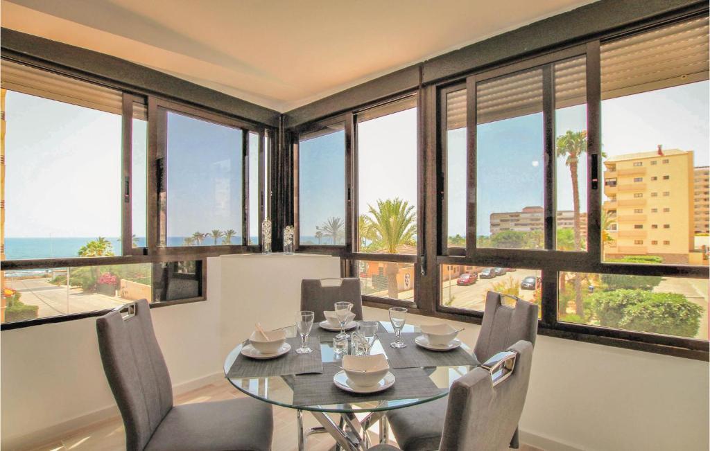 a dining room with a table and chairs and windows at Amazing Apartment In Torrevieja in La Mata