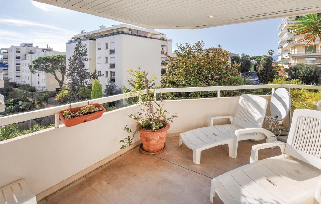 uma varanda com cadeiras brancas e vista para a cidade em Awesome Apartment In Cannes With Kitchen em Cannes