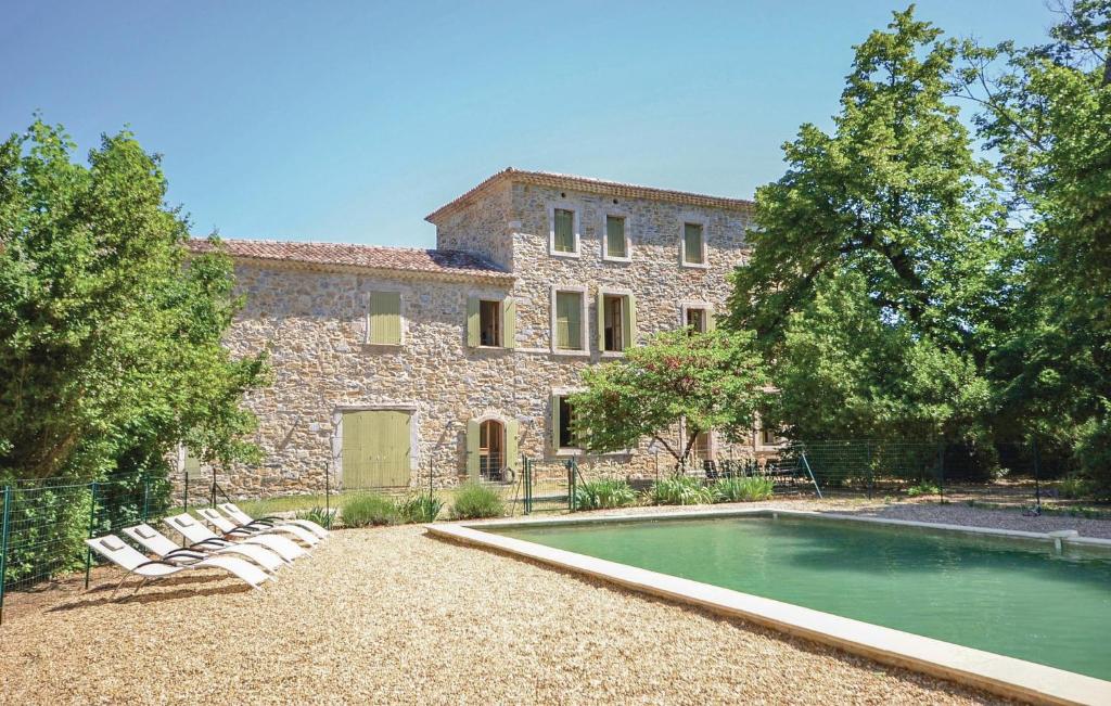 un bâtiment avec une piscine en face d'une maison dans l'établissement Cozy Home In Anduze With House A Mountain View, à Anduze