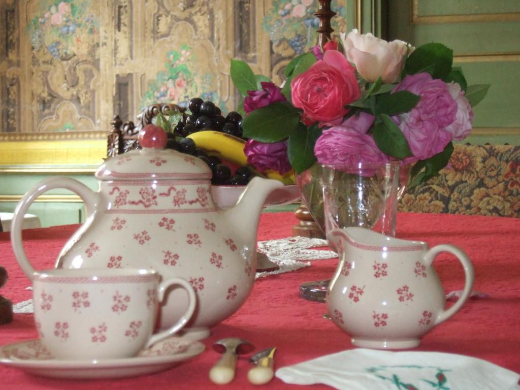 a table with a tea pot and a vase of flowers at Le Ragois in Richelieu