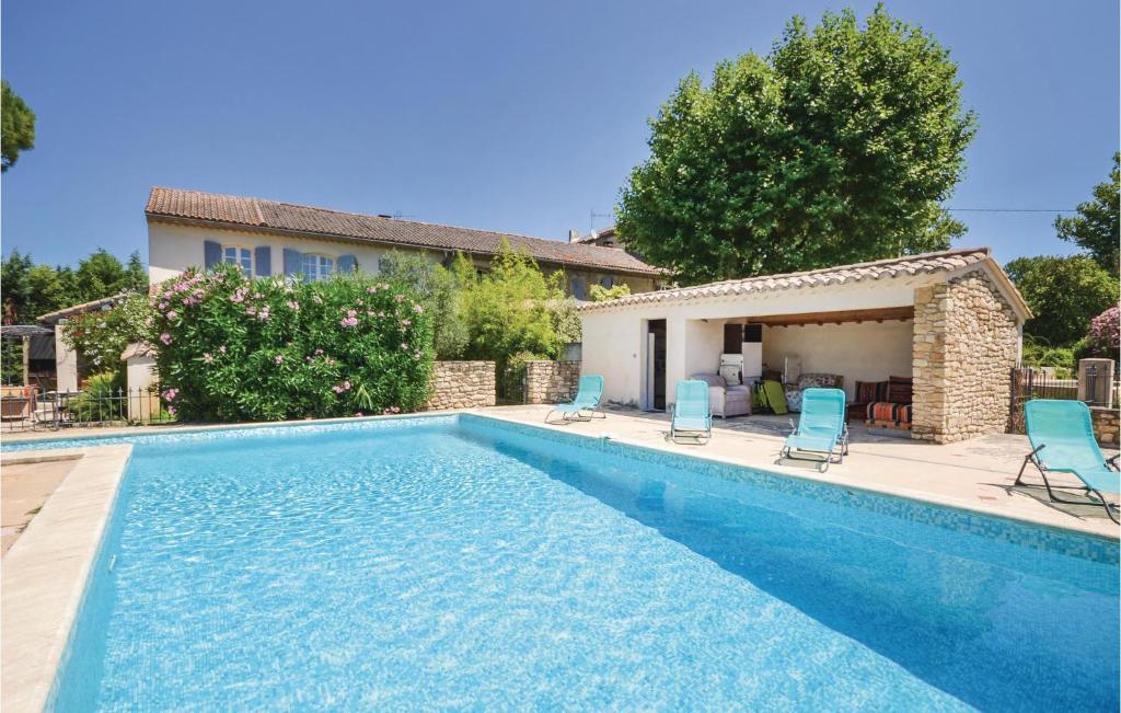 a swimming pool with blue chairs and a house at Mas Melusine in Caderousse