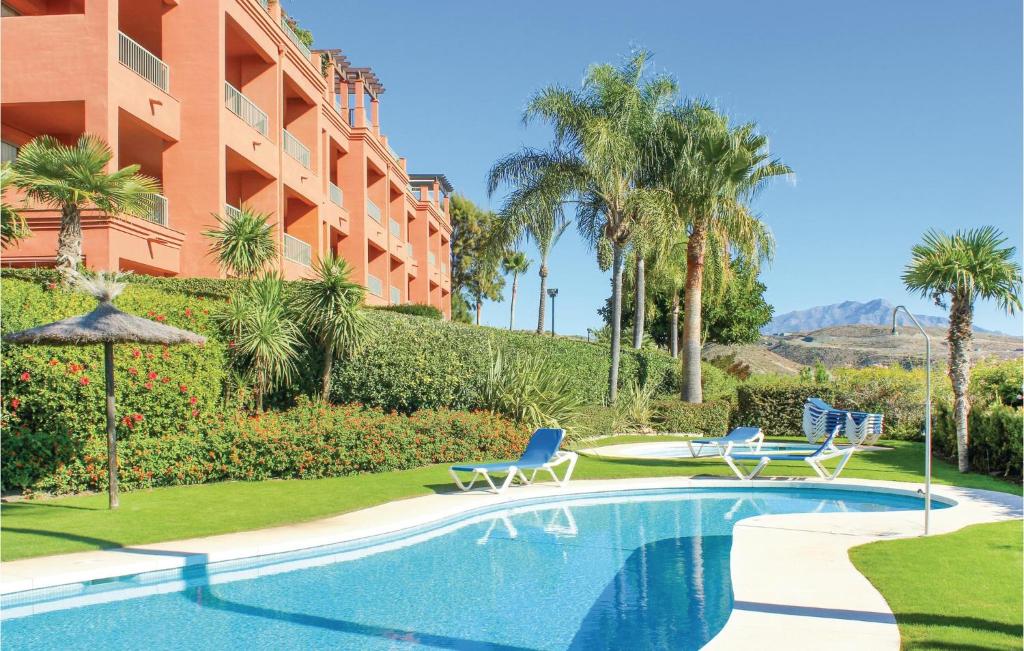 a swimming pool with two chairs and a building at Royal Los Flamingos in Estepona