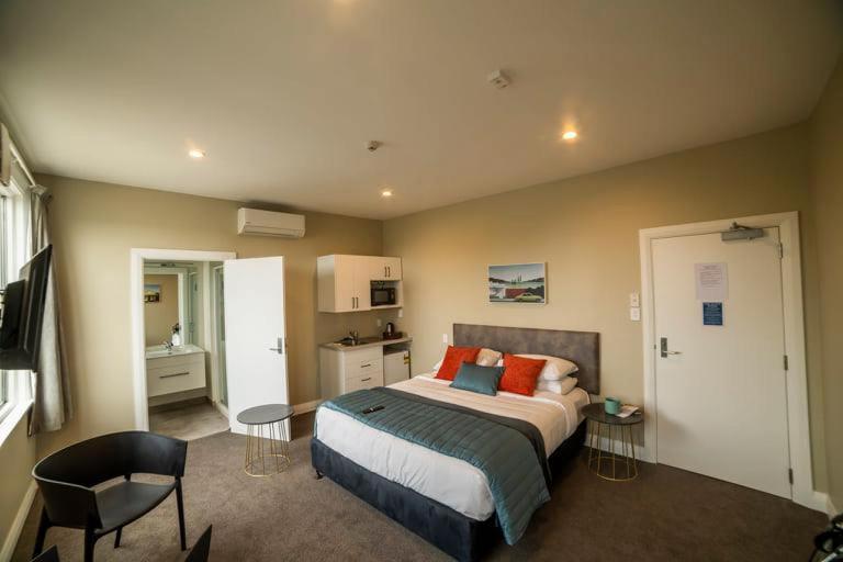 The Amberley Hotel في Amberley: غرفة نوم مع سرير ووسائد برتقالية عليه