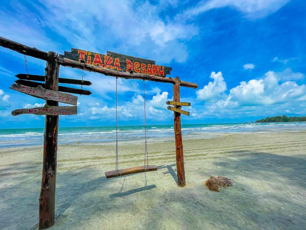 een bord op een strand met een schommel bij Tiara Desaru Seaview Residence in Desaru