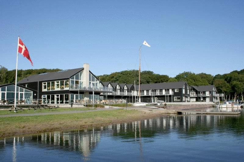 een gebouw met twee vlaggen voor een waterlichaam bij Hotel Strandtangen in Skive