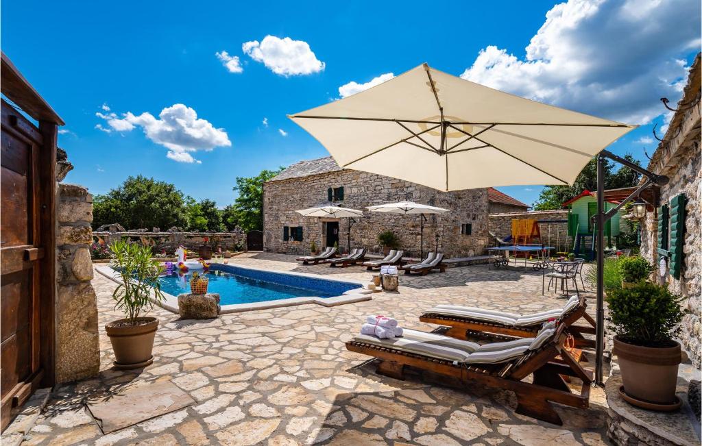 un patio con sombrilla, sillas y piscina en Gorgeous Home In Zelengrad With Kitchen, en Zelengrad