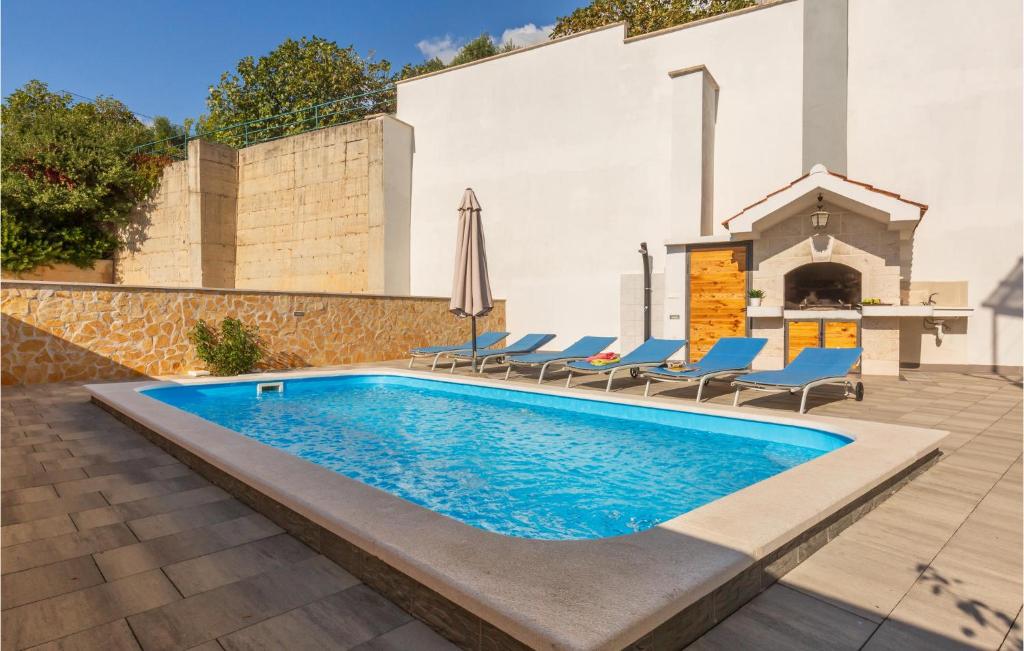 a swimming pool with lounge chairs and a building at 3 Bedroom Lovely Home In Makarska in Makarska