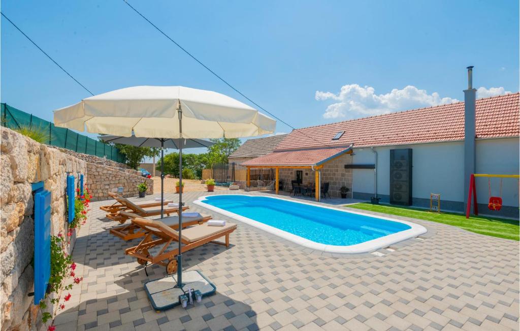 uma piscina com um guarda-sol e cadeiras e uma mesa em Lovely Home In Imotski With Heated Swimming Pool em Imotski