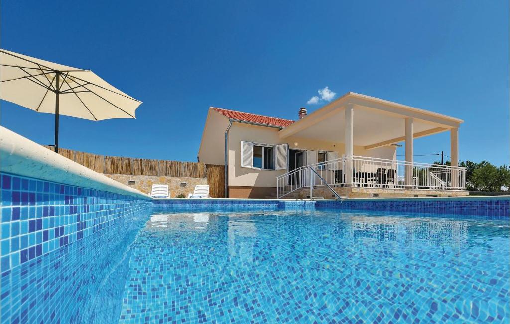 a swimming pool with a house and an umbrella at Gorgeous Home In Krkovic With Outdoor Swimming Pool in Lađevci