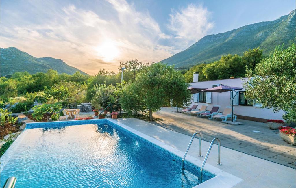 een zwembad in een achtertuin met bergen op de achtergrond bij Nice Home In Vrgorac With Kitchen in Vrgorac