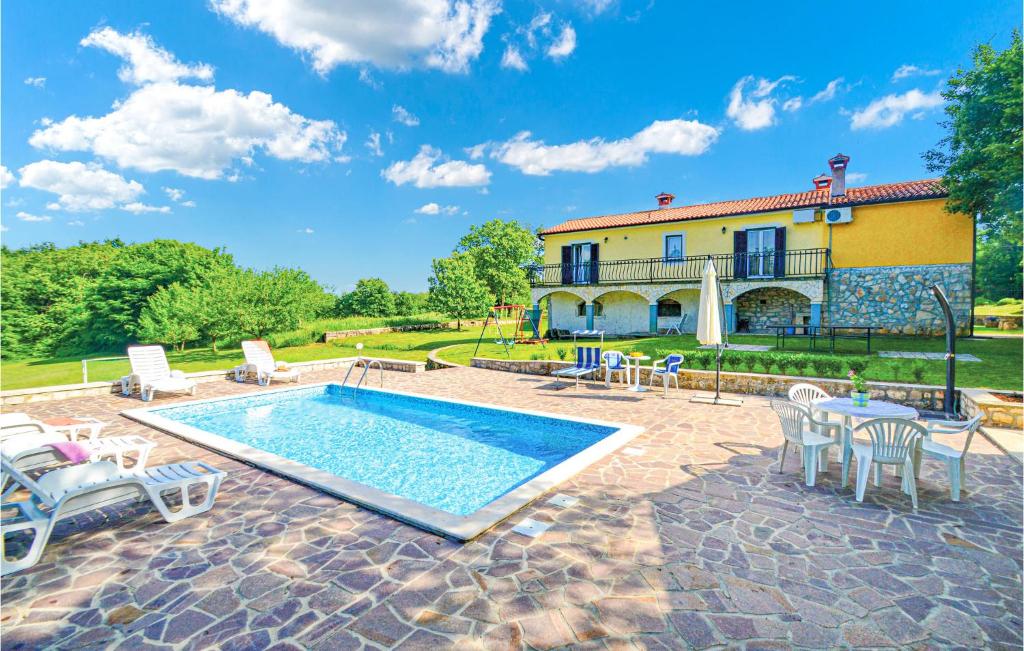 a pool in front of a house with chairs and a table at Awesome Home In Jurani With 4 Bedrooms, Wifi And Private Swimming Pool in Ružići