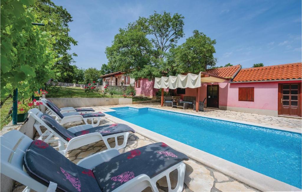 a pool with chaise lounge chairs next to a house at 3 Bedroom Nice Home In Breg in Raša