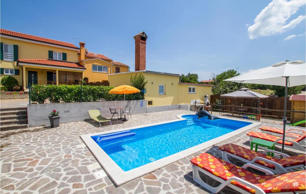 a pool with chairs and umbrellas next to a house at Awesome Home In Labin With Sauna in Labin