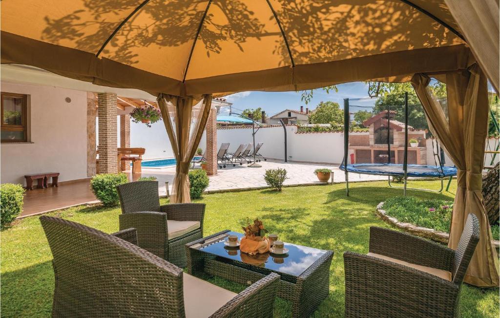 a patio with a table and chairs under a large umbrella at Awesome Home In Barban With Kitchen in Barban