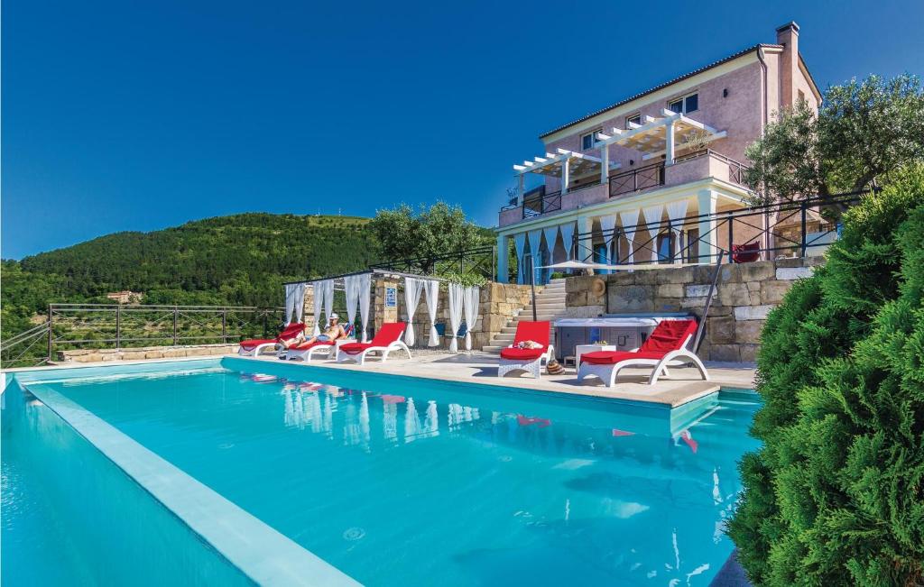 a swimming pool with red chairs and a house at Amazing Home In Pasini With 4 Bedrooms, Internet And Outdoor Swimming Pool in Livade