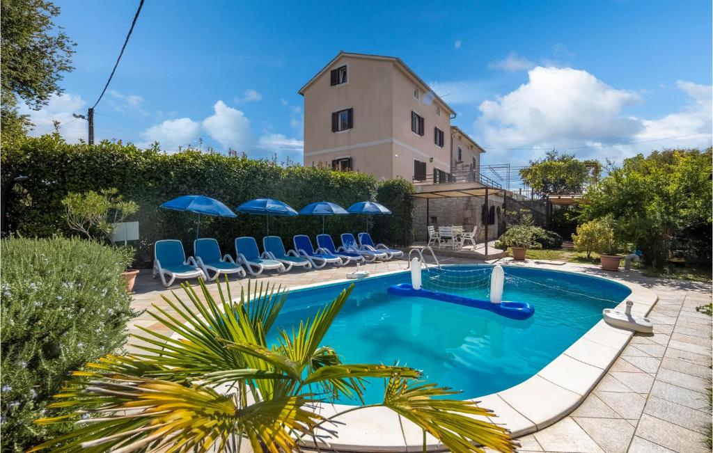 a swimming pool with chairs and a building at 4 Bedroom Lovely Home In Sveti Anton in Sveti Anton