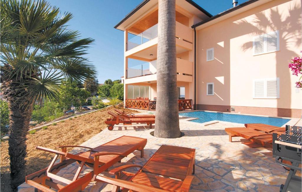 a villa with a swimming pool and wooden furniture at 4 Bedroom Lovely Home In Supetarska Draga in Supetarska Draga