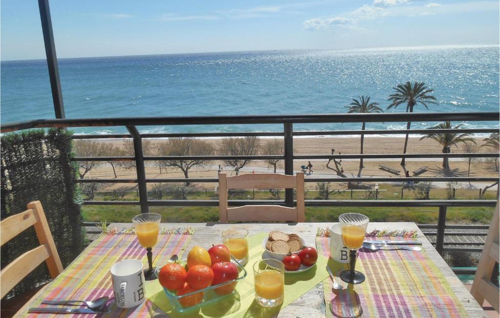 ピネダ・デ・マールにあるStunning Apartment In Pineda De Mar With House Sea Viewのビーチ沿いのバルコニーにテーブル(フルーツ、ジュース付)