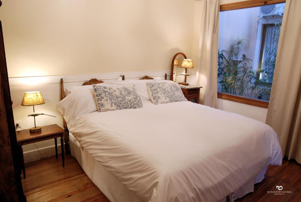 a bedroom with a white bed with two lamps and a window at Casa Viva Hotel Boutique in Junín
