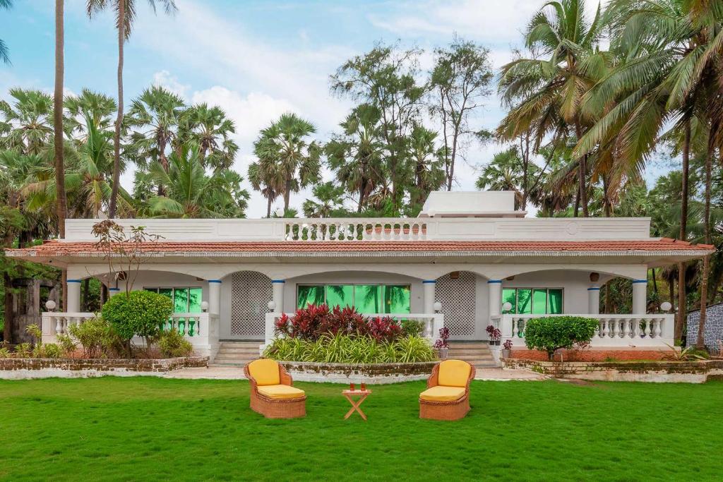 StayVista's Villa Bharat - Beachfront serenity with A spacious lawn في مومباي: منزل أبيض مع كراسي في الفناء