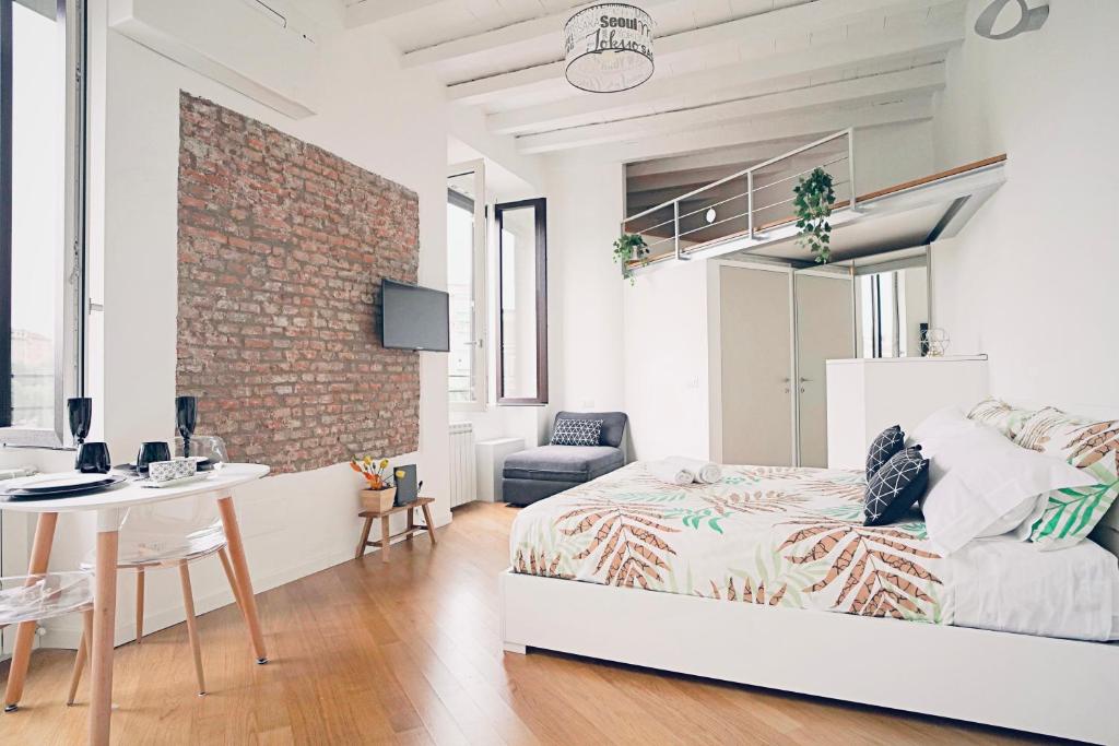 a bedroom with a bed and a desk and a brick wall at P&D Apartments Darsena in Milan