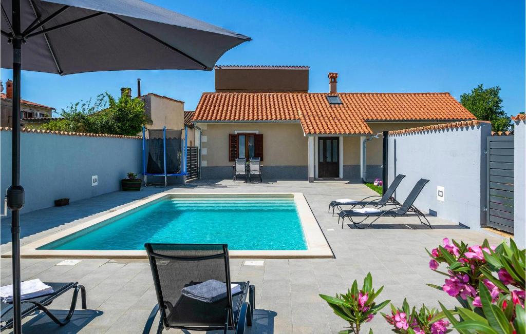 einen Pool mit 2 Stühlen und einem Sonnenschirm in der Unterkunft Beautiful Home In Loborika With Kitchen in Loborika