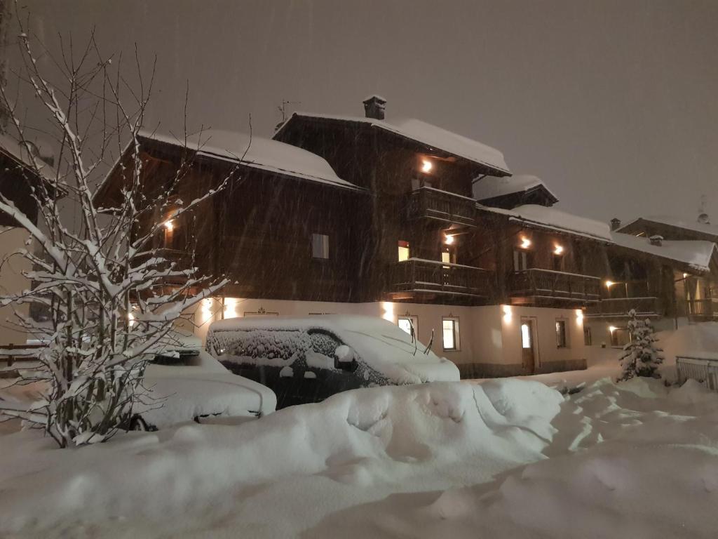 una casa cubierta de nieve por la noche con luces en Al Camanel, en Livigno