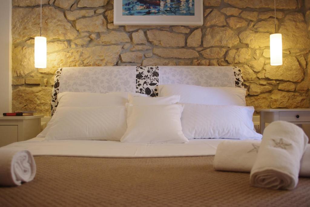 a bed with white pillows and a stone wall at Guest House Villa Dagmar in Crikvenica