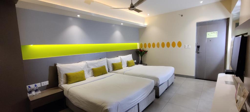 a hotel room with two beds and a yellow stripe on the wall at ZIBE Hyderabad by GRT Hotels in Hyderabad