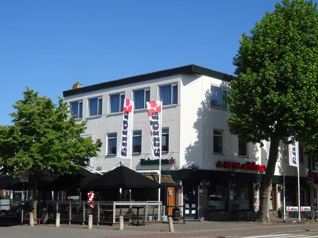 een wit gebouw met vlaggen ervoor bij Hotel Café Restaurant Abina in Amstelveen