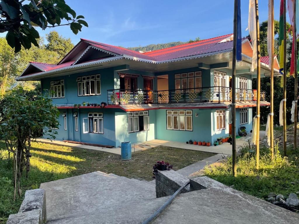 una casa azul con techo rojo en KHIMSHA HOMESTAY, en Pelling