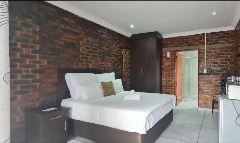 um quarto com uma cama grande e uma parede de tijolos em Zea 85 BnB em Vereeniging