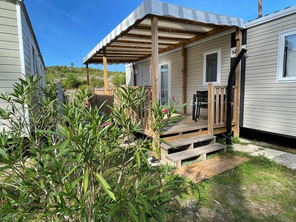 a house with a porch with a wooden deck at Camping Les dunes de Contis chez Nelly&Thomas in Saint-Julien-en-Born