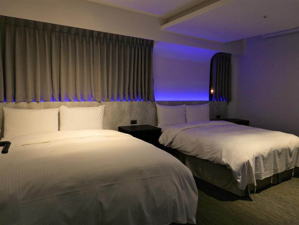 台北市にある泊居旅店二館 Oursinn Hotel 2の紫色の照明が備わるホテルルーム内のベッド2台
