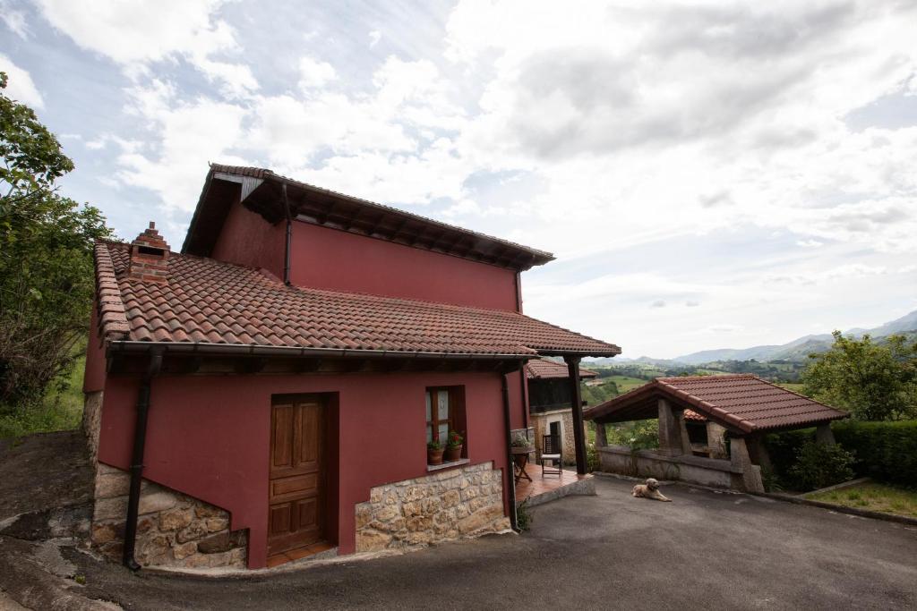 a red house with a dog sitting in front of it at Casa Vacacional Miyares in La Estrada