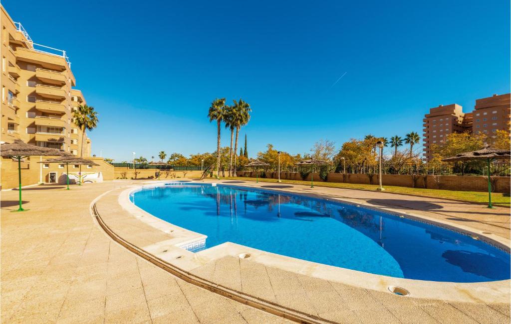 a large swimming pool with palm trees and a building at Beautiful Apartment In Oropesa Del Mar With 2 Bedrooms, Wifi And Outdoor Swimming Pool in Oropesa del Mar