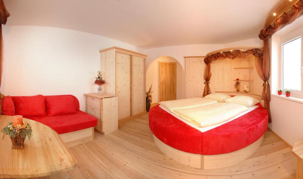 a bedroom with a large bed and a red couch at Bed & Breakfast Landhaus Strasser in Söll