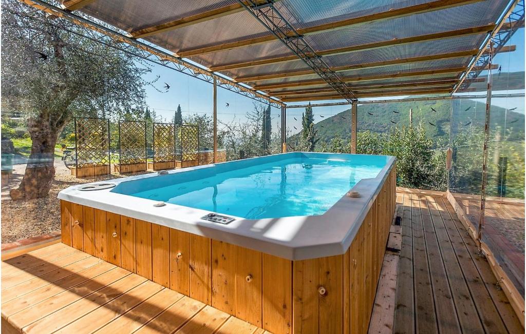 una bañera de hidromasaje en una terraza de madera con una pared de cristal en Casa I Gelsi, en Tre Colli