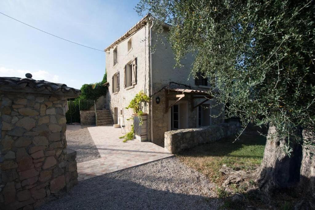 un bâtiment en pierre avec un arbre en face dans l'établissement Le mas des biches, à Le Rouret