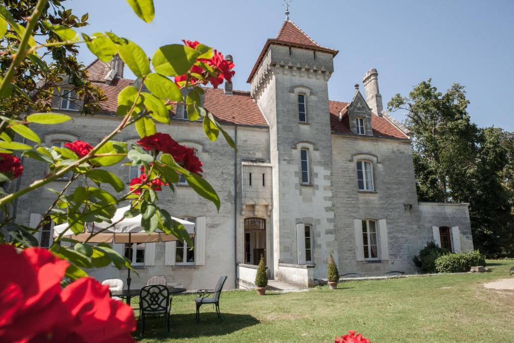 un vieux château avec des fleurs rouges devant lui dans l'établissement Château des Salles, à Saint-Fort-sur-Gironde