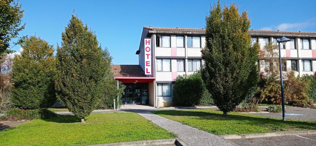 un bâtiment avec des arbres devant lui dans l'établissement Résidence Hôtelière des Ondes, à Saint-Lys