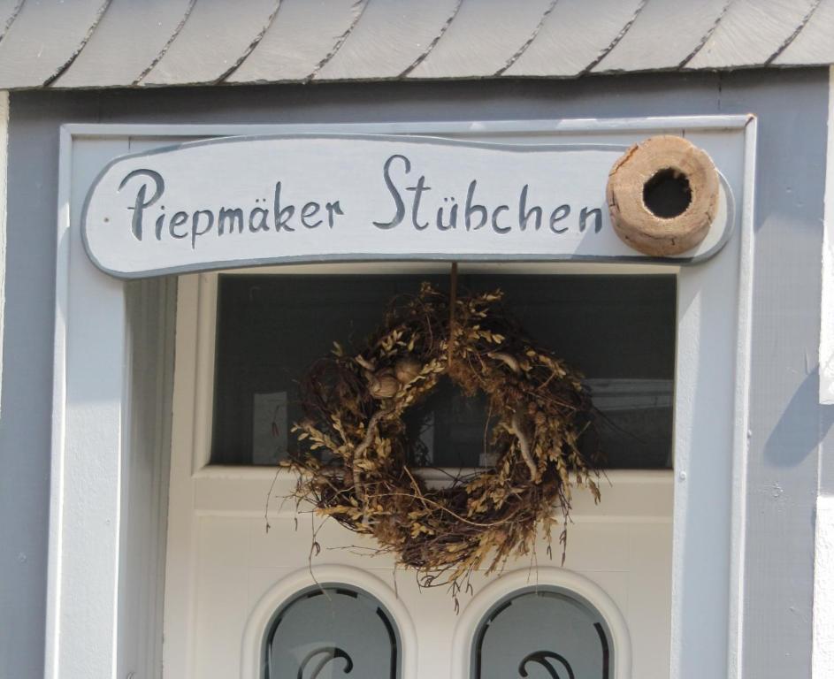 ein Schild an einer Tür mit einem Kranz darauf in der Unterkunft Piepmäker Stübchen in Goslar