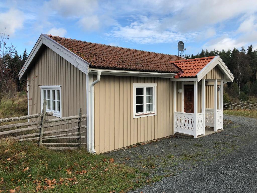 a small yellow building with a fence and a house at Gården Ekön in Forserum