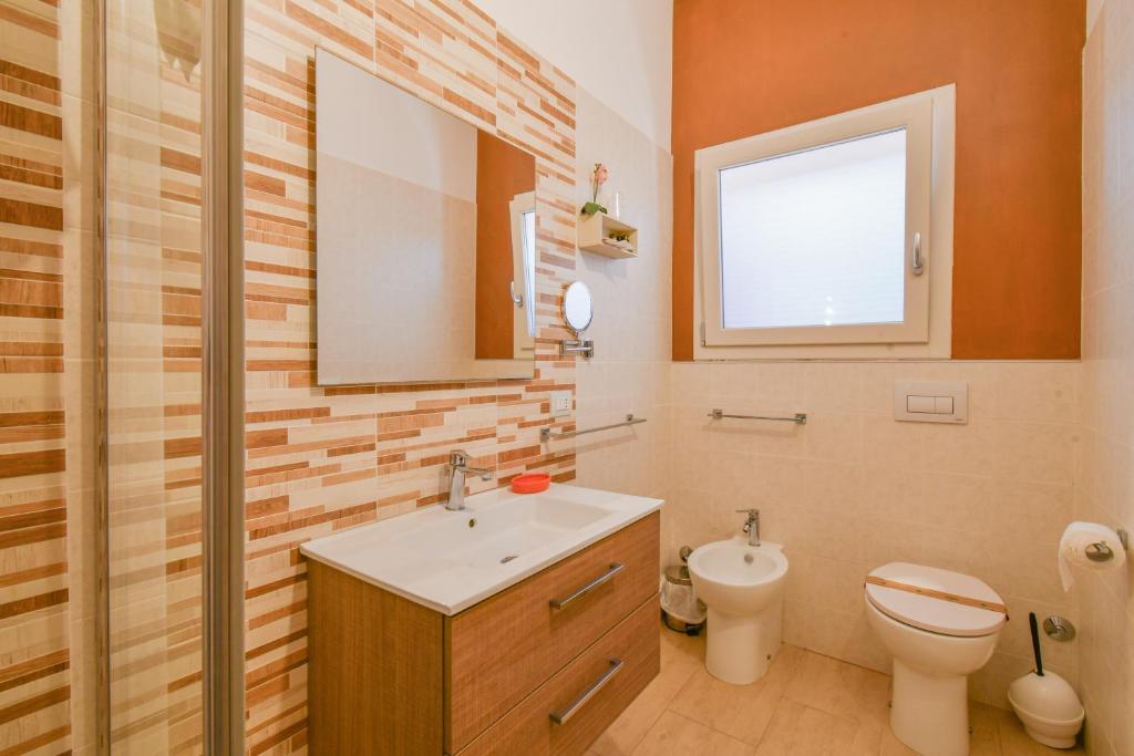 a bathroom with a sink and a toilet and a mirror at Calasole Country House in Torre Lapillo