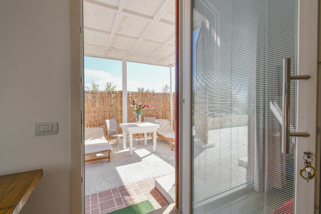 a glass door leading to a patio with a table at Calasole Country House in Torre Lapillo
