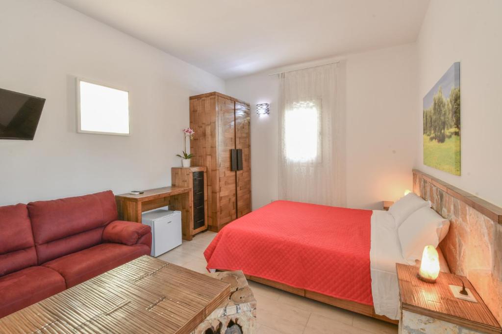 a bedroom with a red bed and a couch at Calasole Country House in Torre Lapillo