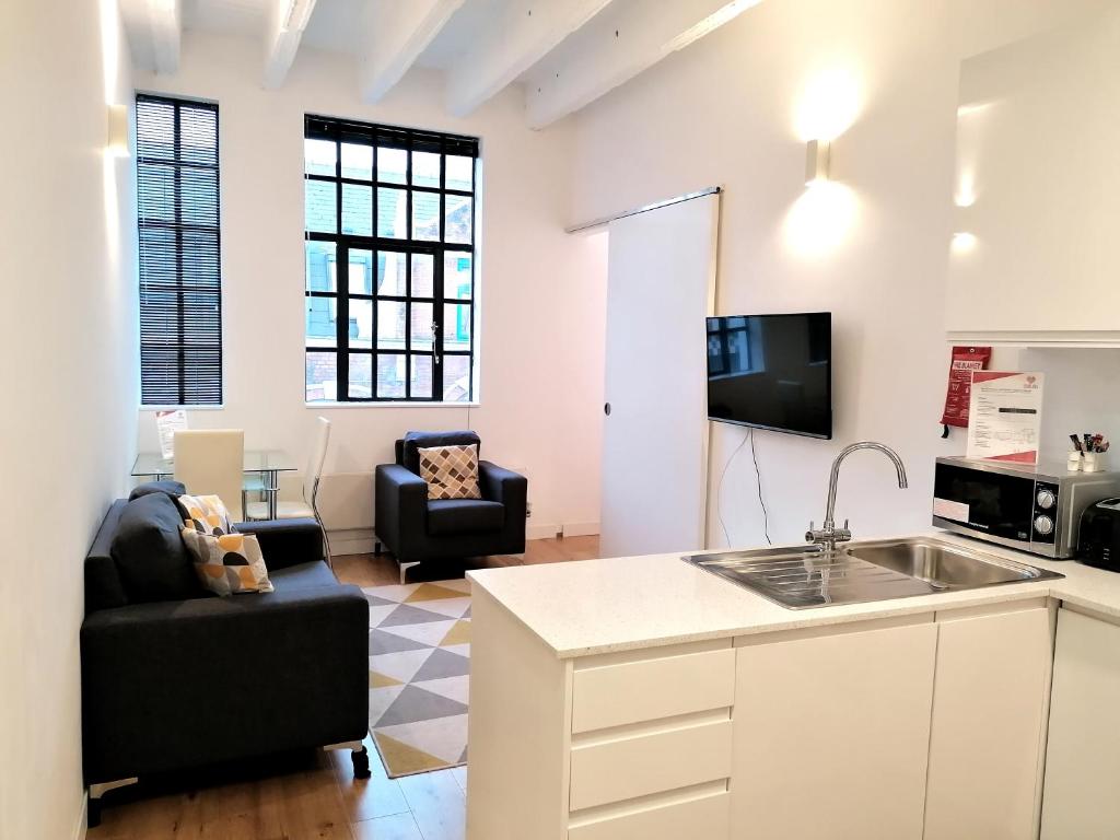a kitchen and living room with a sink and a couch at Leather Lane Serviced Apartments in London