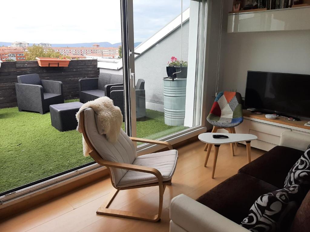 a living room with a chair and a large window at Atico en el centro de Vitoria in Vitoria-Gasteiz