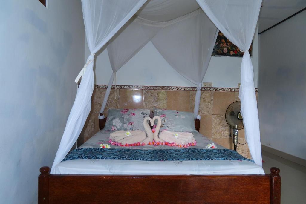a canopy bed with two flamingos on it at Pondok Lembah Dukuh Homestay in Tirtagangga